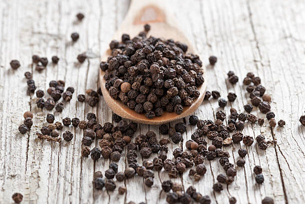 wooden spoon with peppercorns on rustic foreground and background